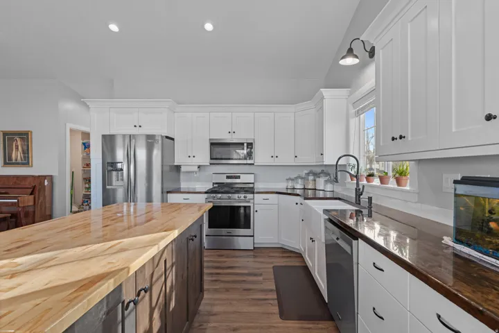 Kitchen featuring appliances with stainless steel finishes, white cabinetry, butcher block countertops, dark wood-type flooring, and recessed lighting