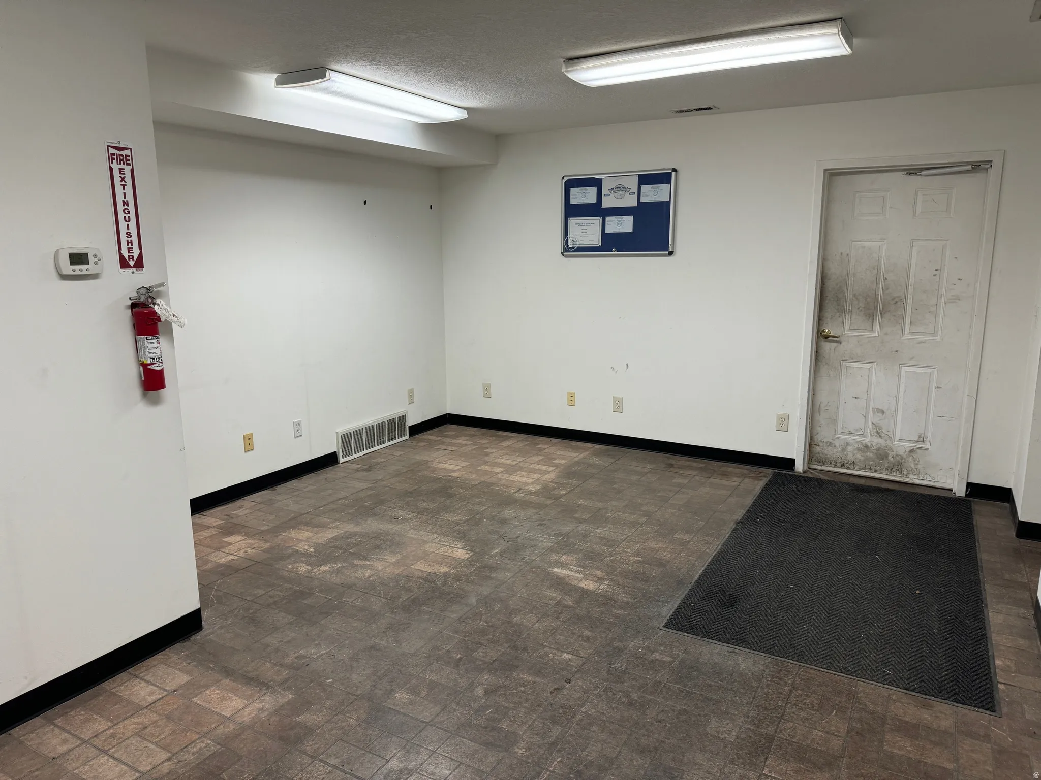 Empty room featuring brick patterned floors and a textured ceiling