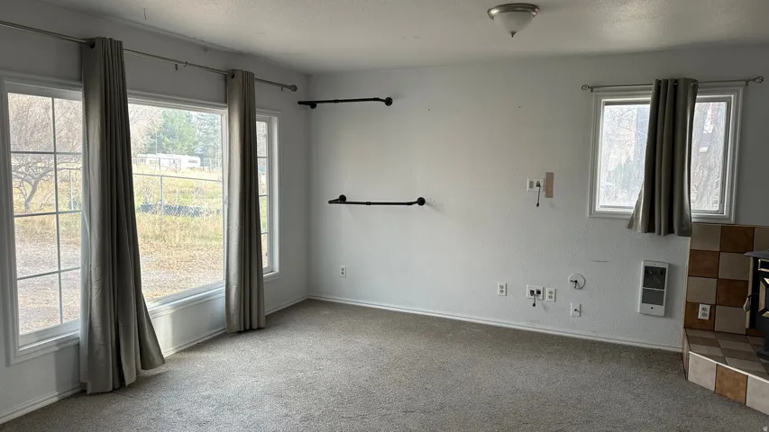 Carpeted spare room with a textured ceiling and heating unit
