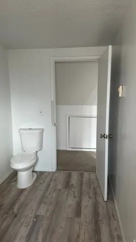Half bathroom featuring toilet and dark wood finished floors
