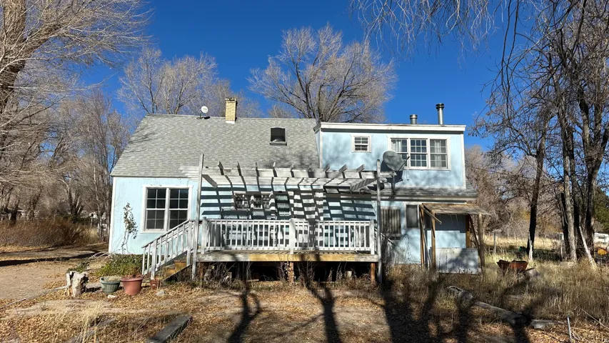 Rear view of house with a deck, a chimney, and a shingled roof