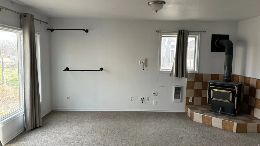 Unfurnished living room featuring a wood stove, carpet floors, and heating unit