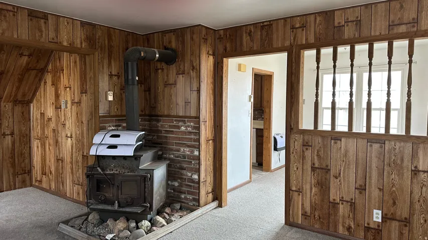 Interior space featuring wooden walls, a wood stove, carpet floors, and heating unit