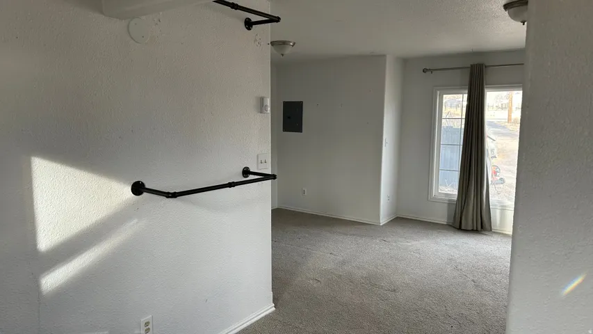 Carpeted spare room with a textured wall, a textured ceiling, and electric panel