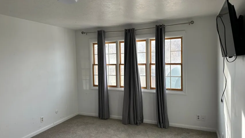 Carpeted spare room with a textured ceiling and baseboards