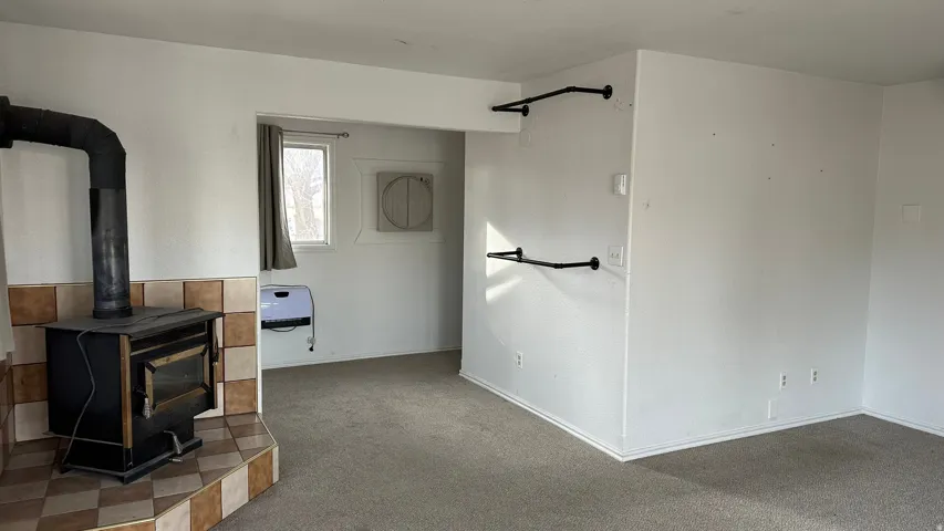 Unfurnished living room with a wood stove, carpet, and heating unit