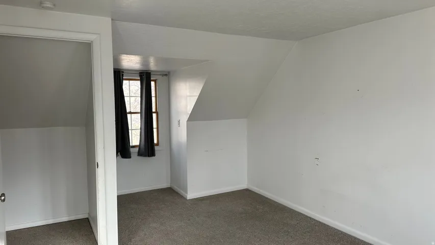 Bonus room with carpet floors, lofted ceiling, and a textured ceiling