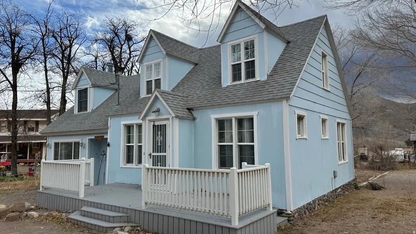 View of front of property with a wooden deck and roof with shingles