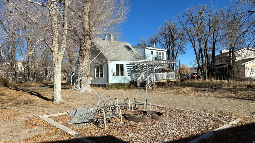 Rear view of property with an outdoor fire pit, a chimney, a deck, and a shingled roof