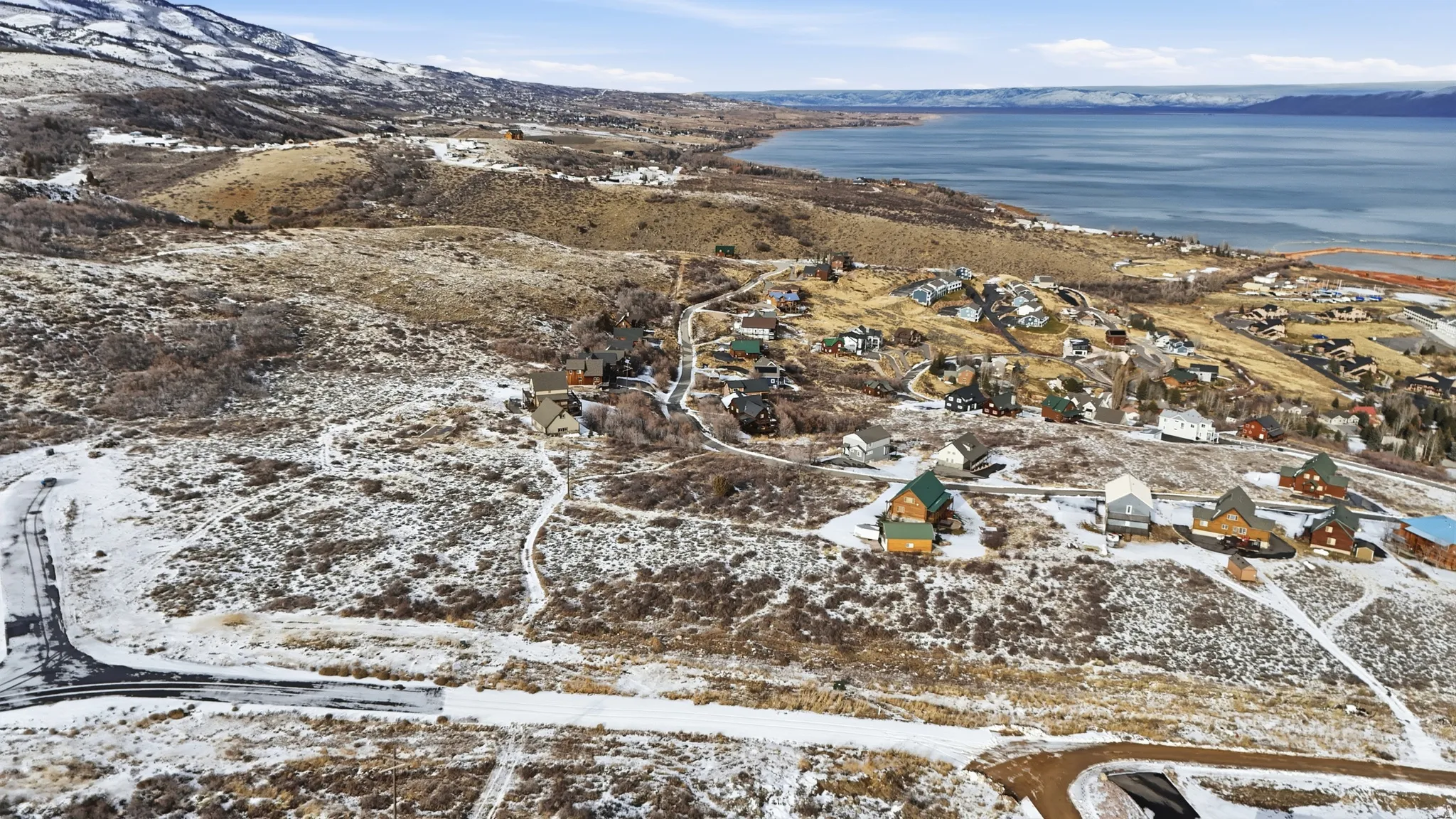 Snowy aerial view with a water and mountain view and a residential view