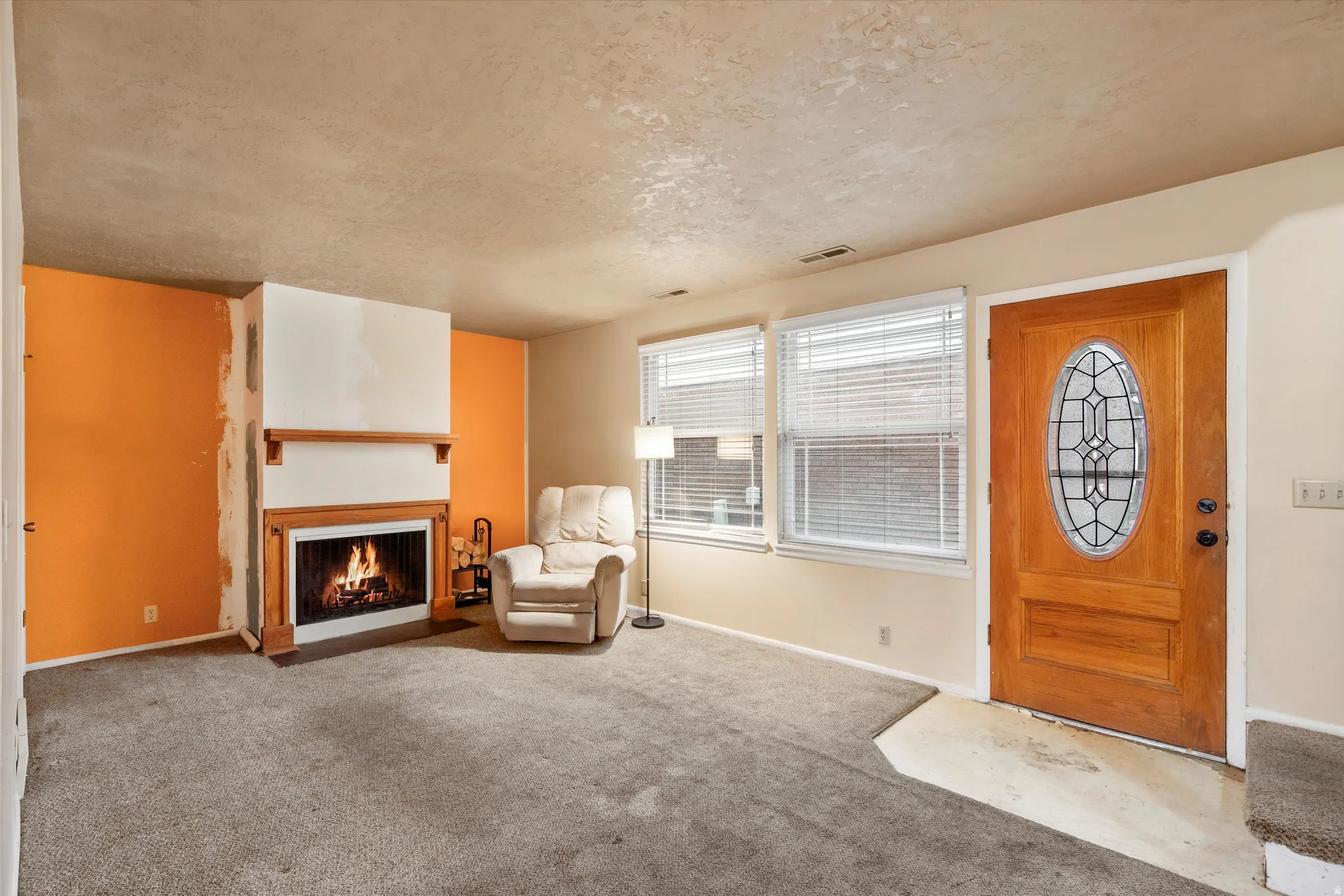 Carpeted entrance foyer with a fireplace with flush hearth and a textured ceiling