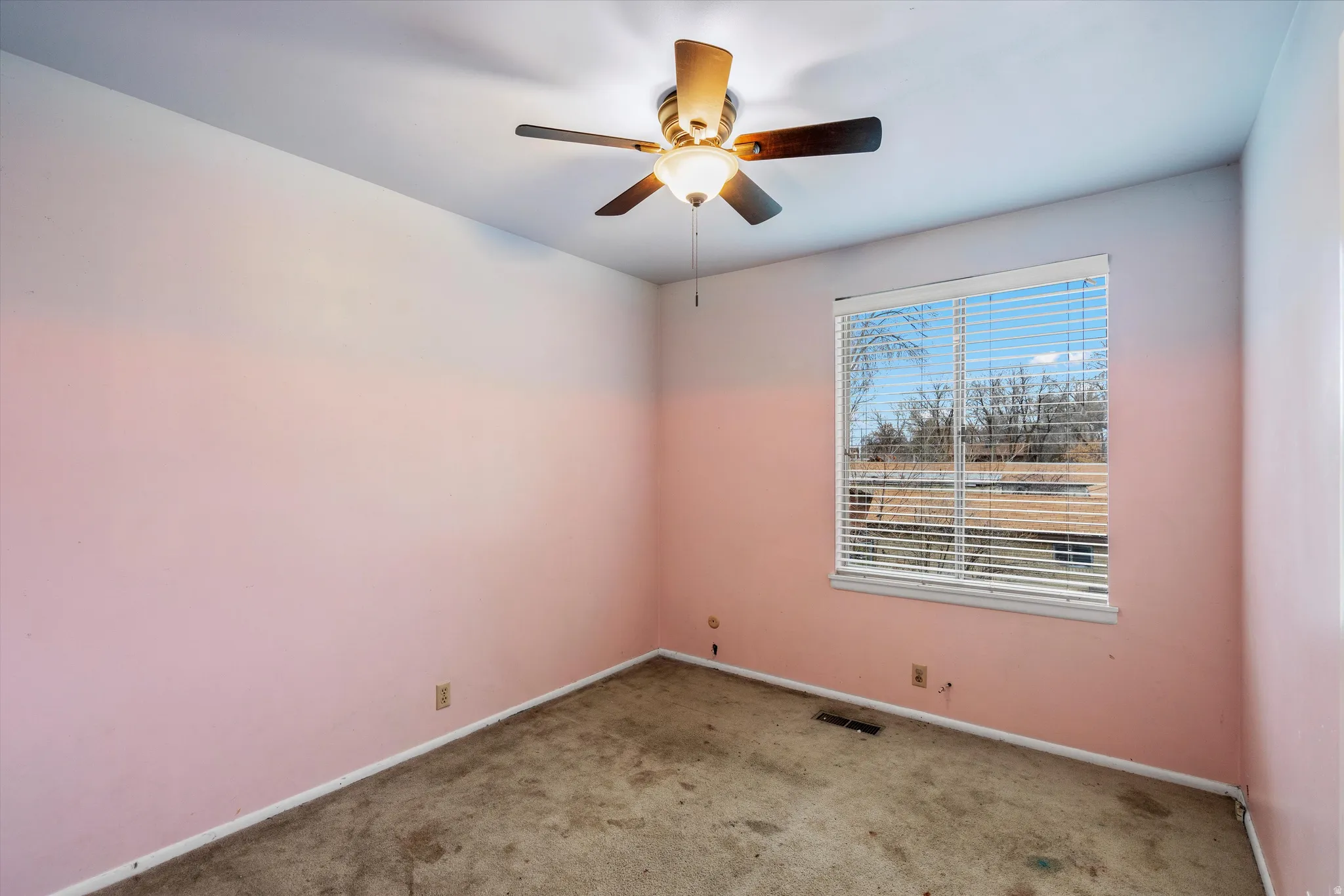 Carpeted empty room with ceiling fan and baseboards