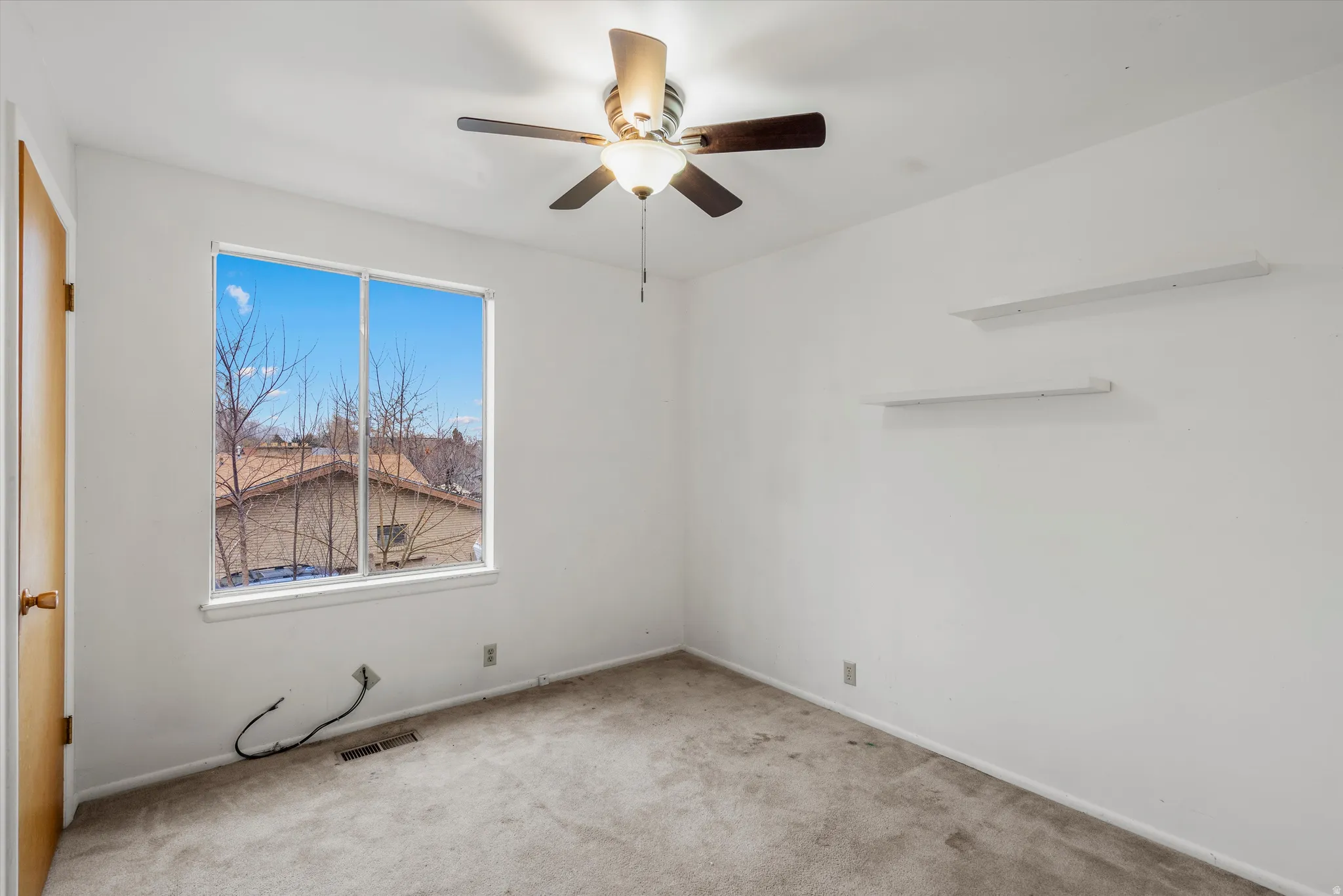 Carpeted empty room featuring a ceiling fan and baseboards