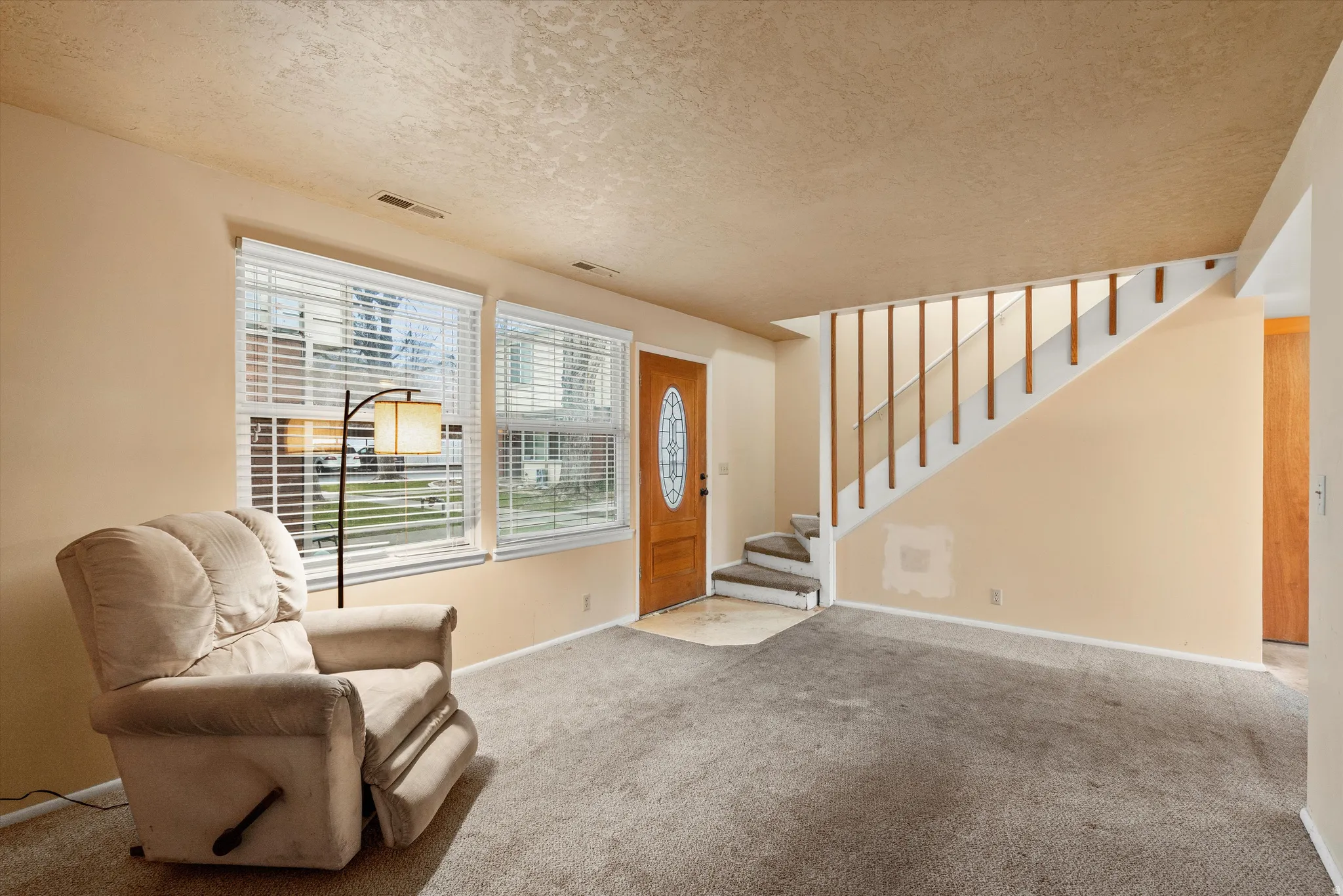 Carpeted foyer featuring a textured ceiling and stairway