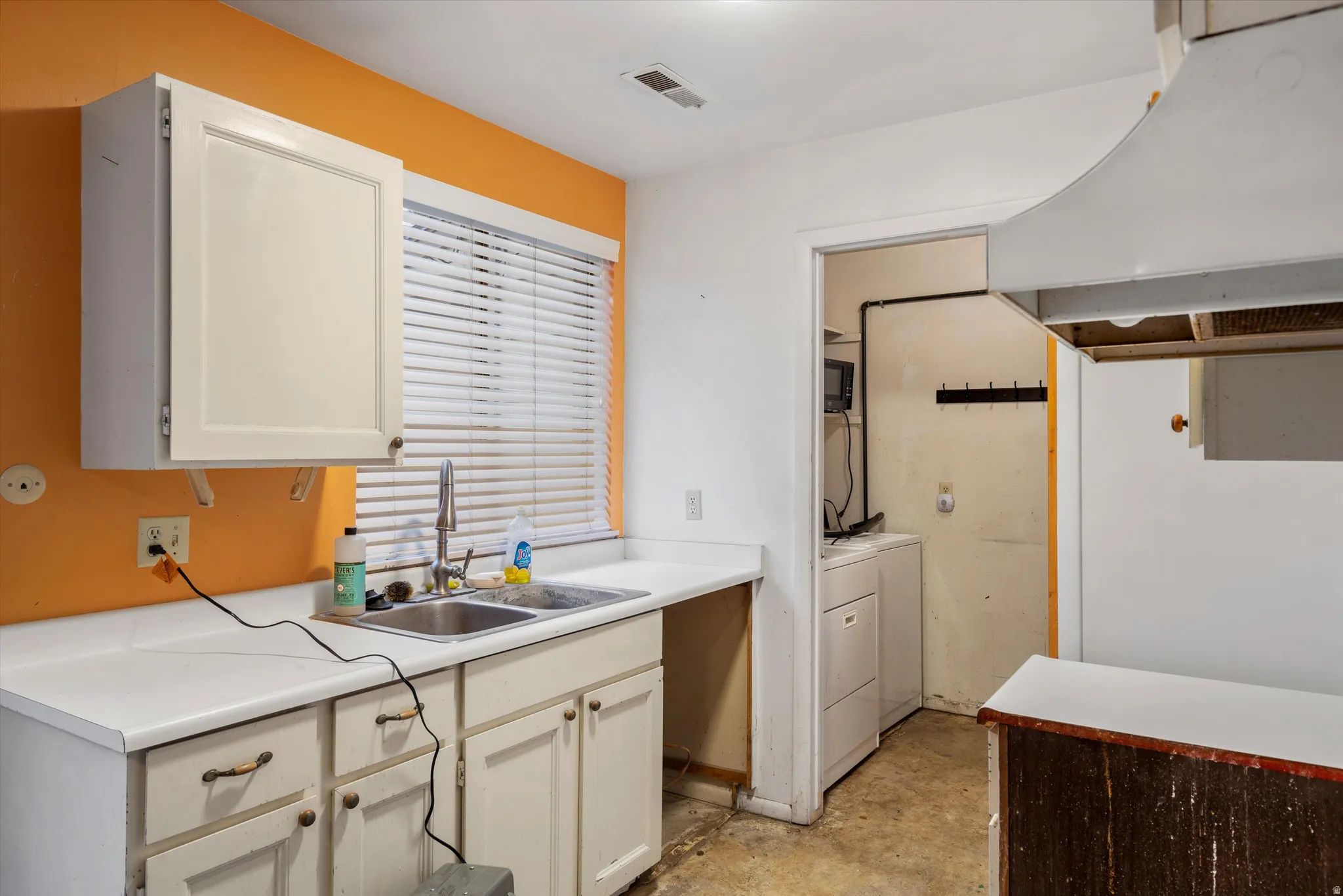 Kitchen featuring light countertops, washer / clothes dryer, and concrete flooring