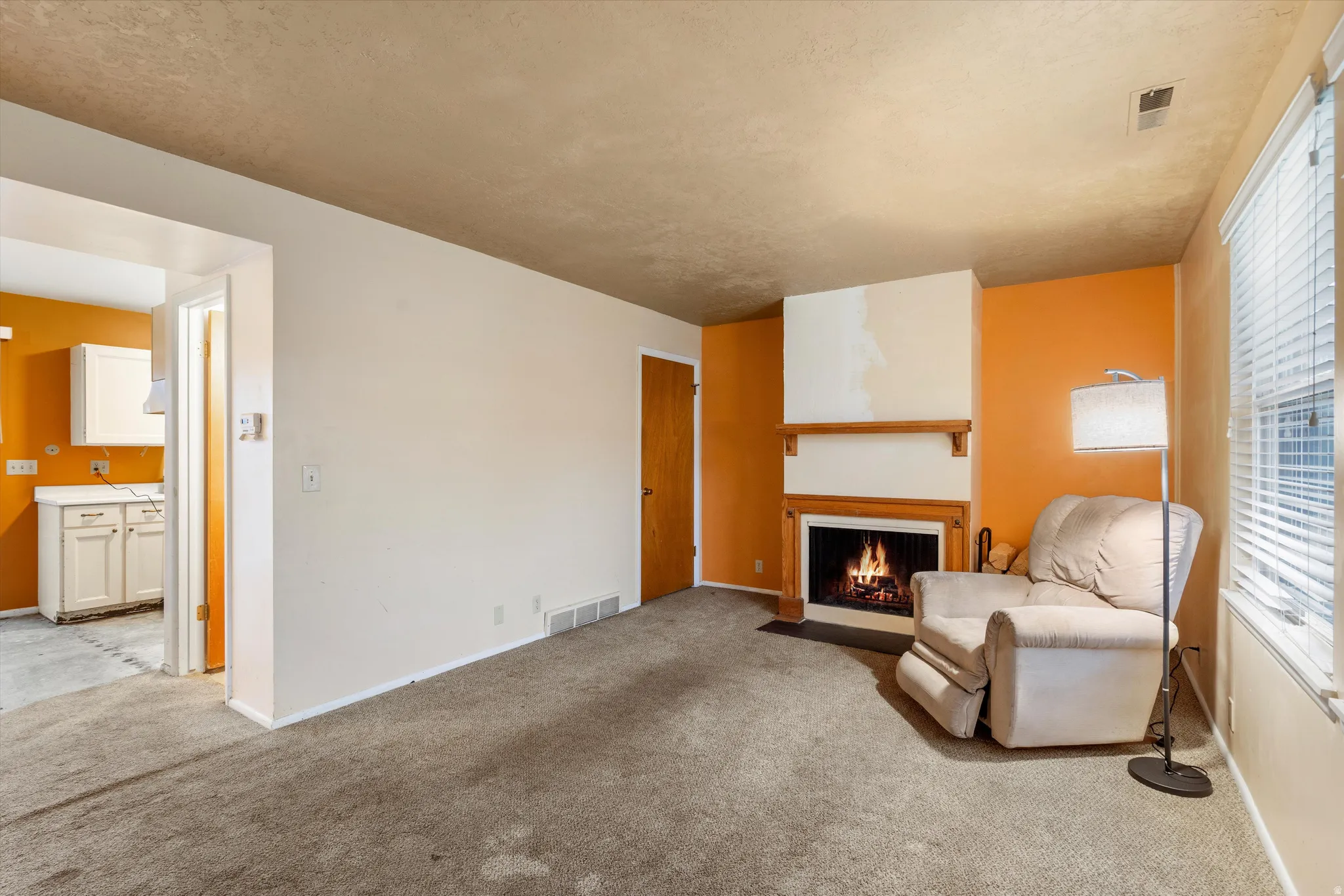 Living area featuring a fireplace with flush hearth and light colored carpet