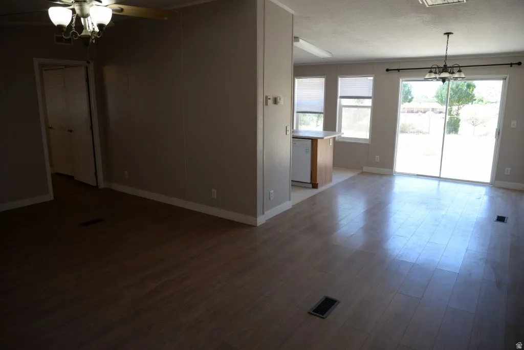 Unfurnished living room with a chandelier, a textured ceiling, and dark wood-style floors