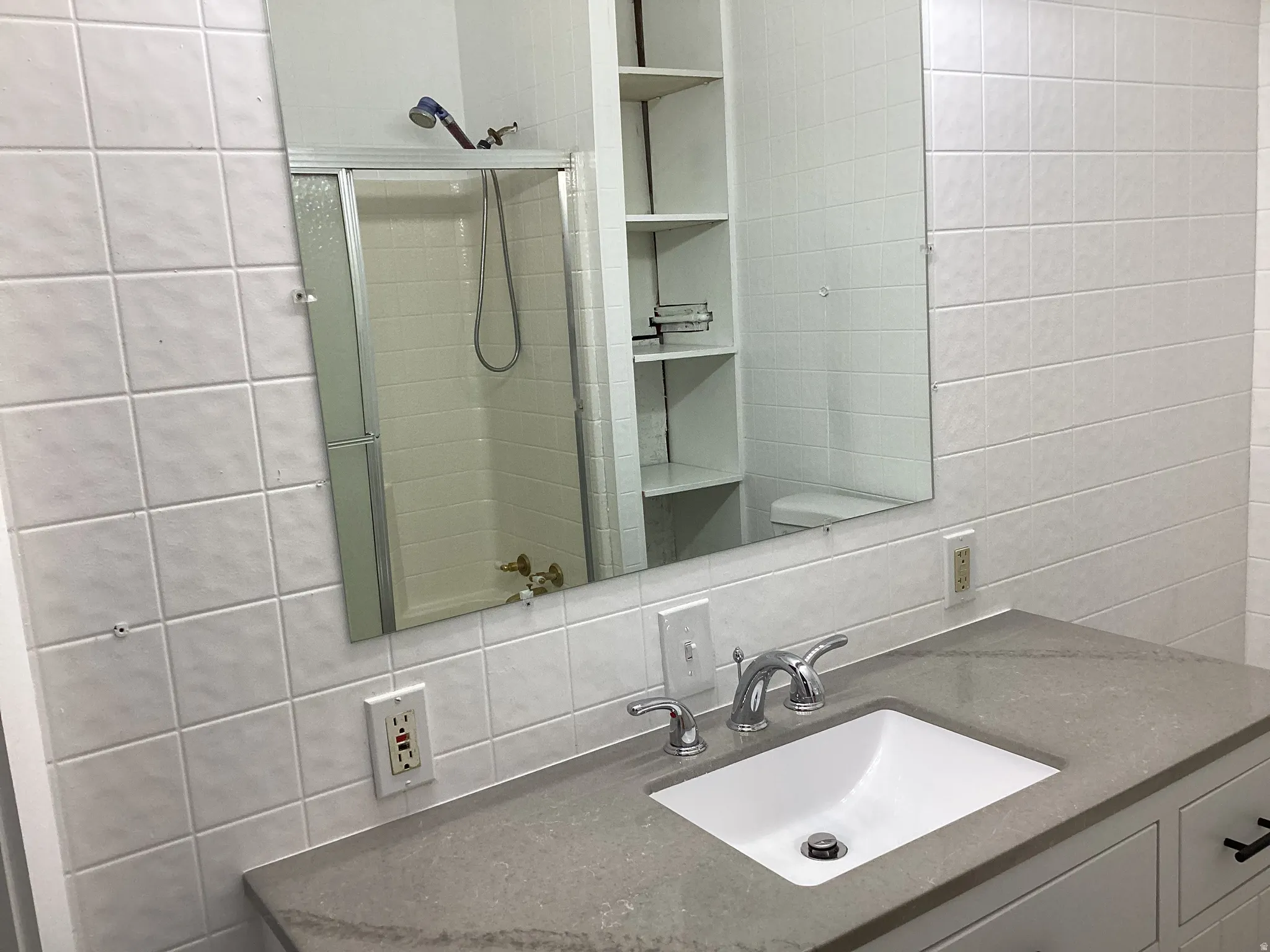 Bathroom with vanity, a shower stall, tile walls, and decorative backsplash