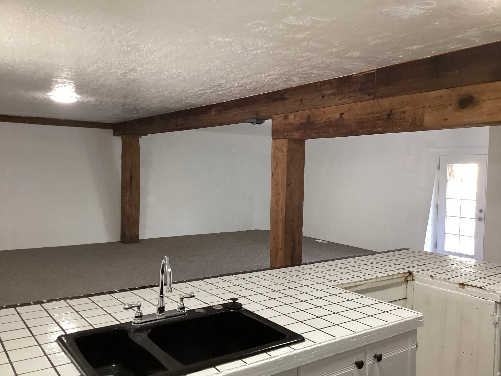 Kitchen with tile counters, white cabinets, and a textured ceiling