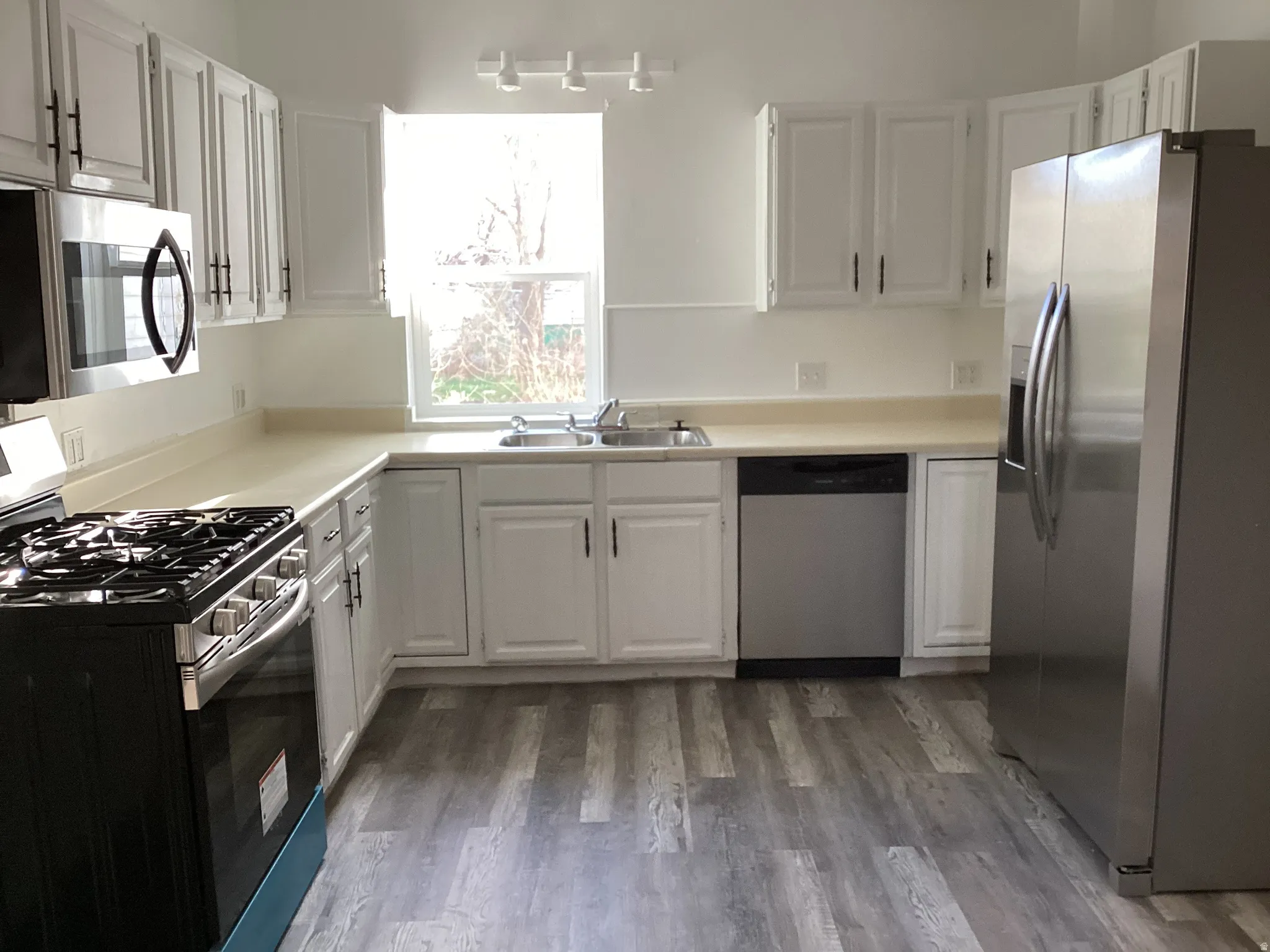 Second Kitchen with stainless steel appliances, light countertops, white cabinetry, and dark wood-style floors