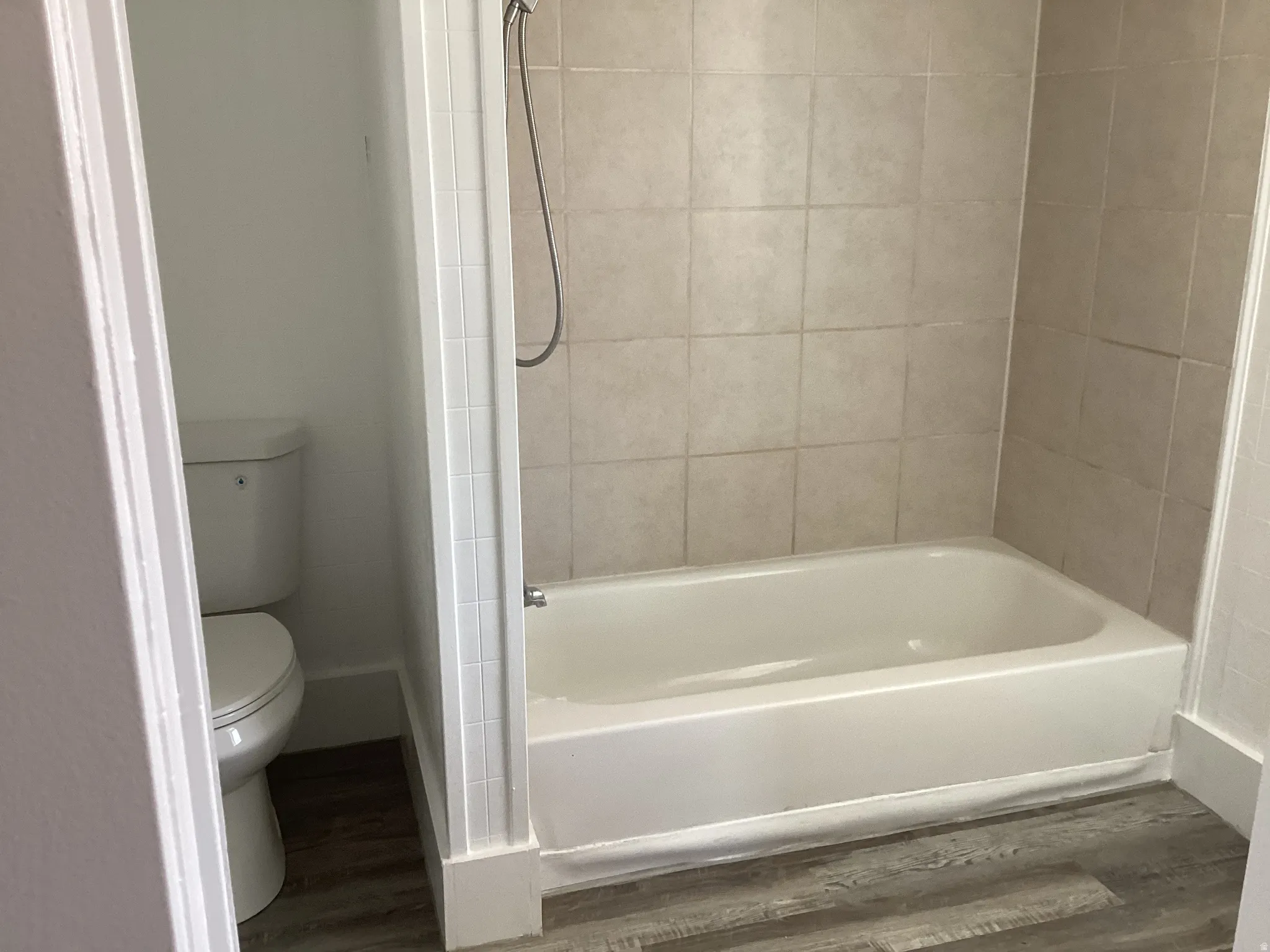 Bathroom with wood finished floors and shower / washtub combination