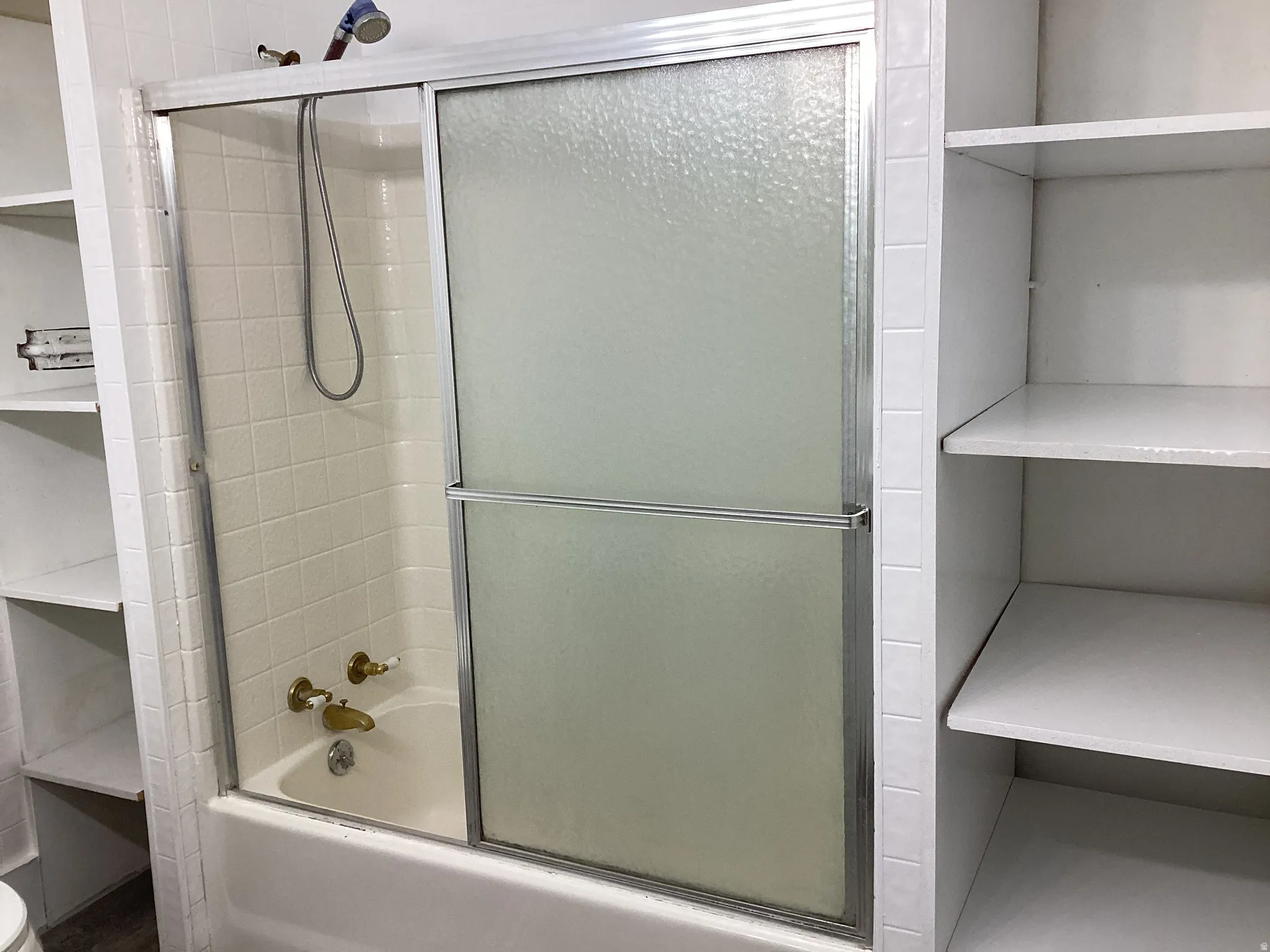 Full bath with enclosed tub / shower combo and lots of linen shelves