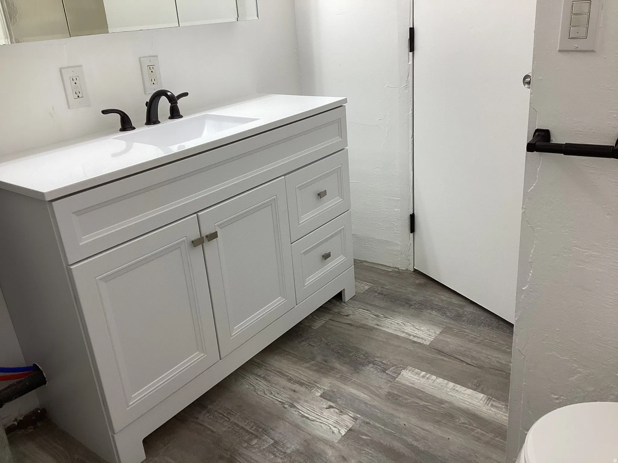 3/4 bath with light wood-style floors and vanity