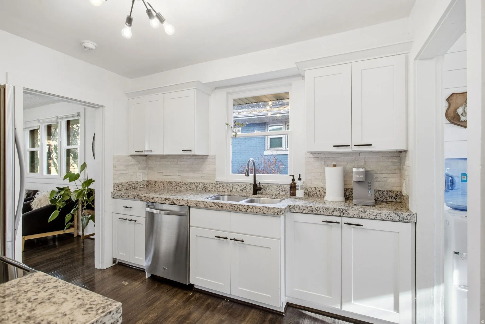 Kitchen with stainless steel appliances, white cabinets, tasteful backsplash, dark wood finished floors, and light stone countertops