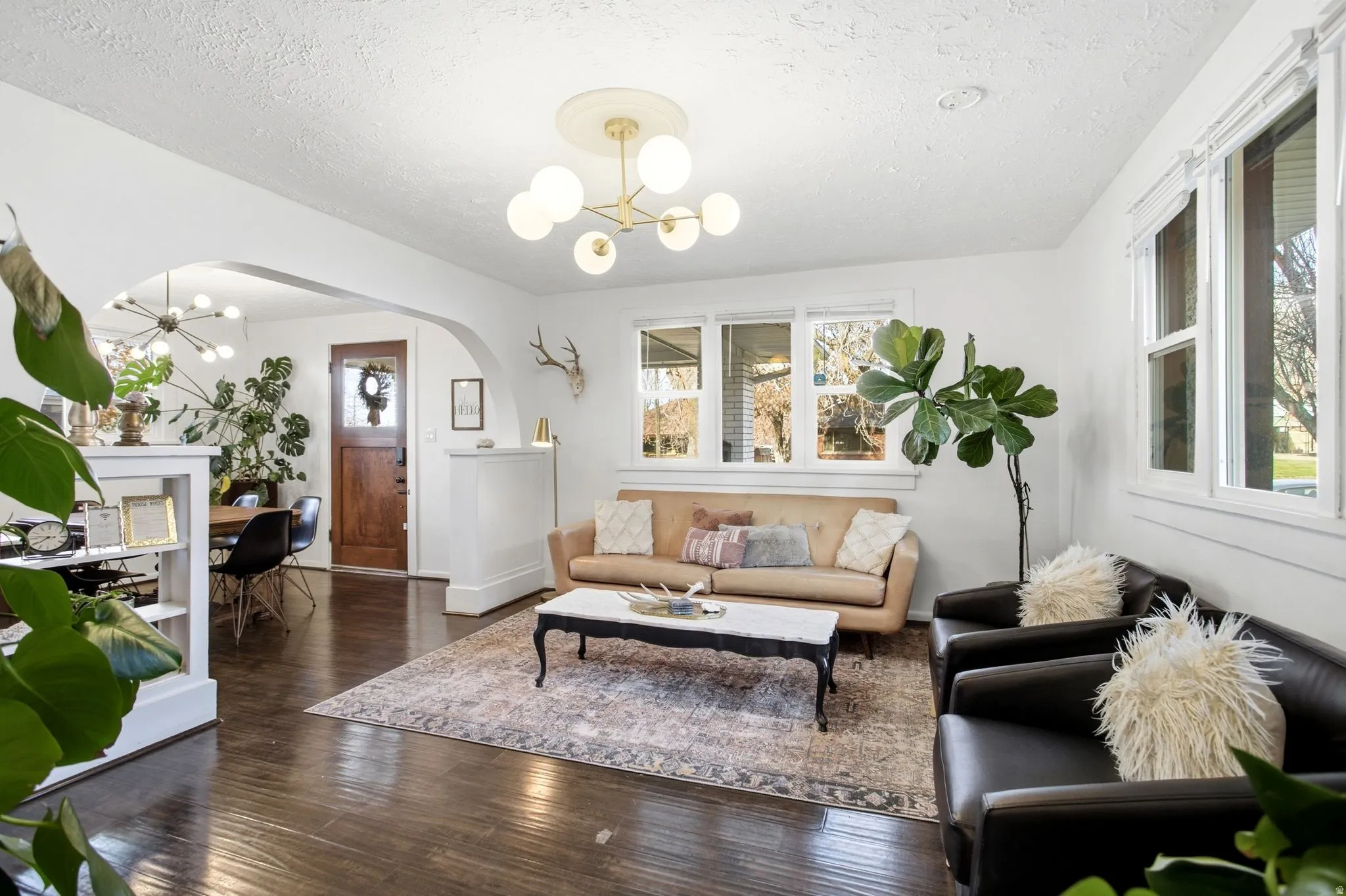 Living room featuring a chandelier, a textured ceiling, dark wood finished floors, and arched walkways