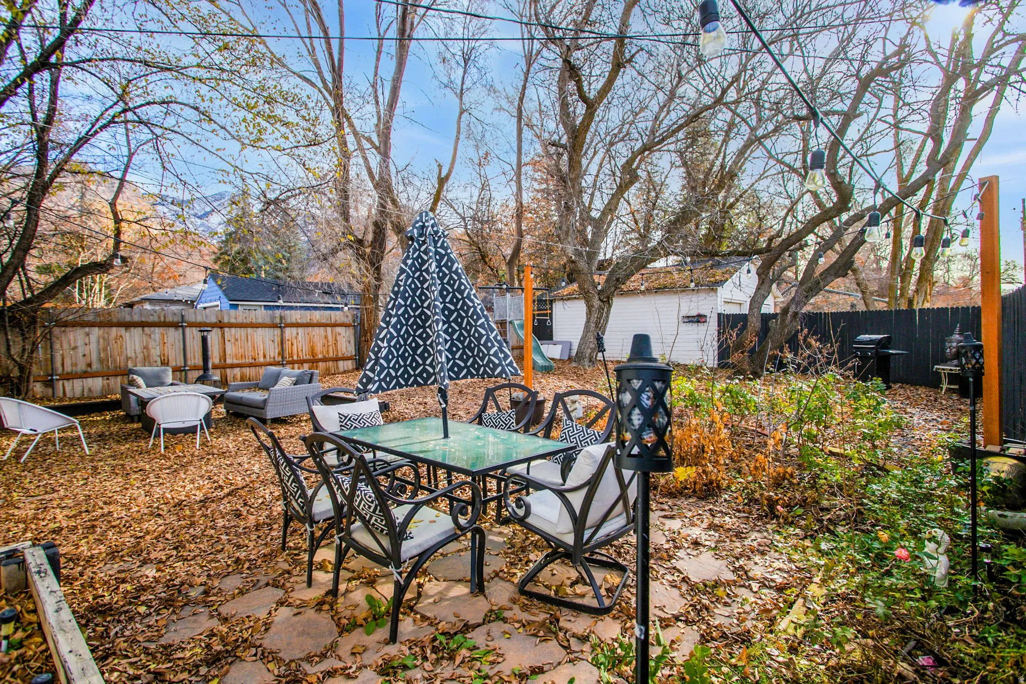 Fenced backyard with a patio, grilling area, outdoor dining space, and an outdoor structure