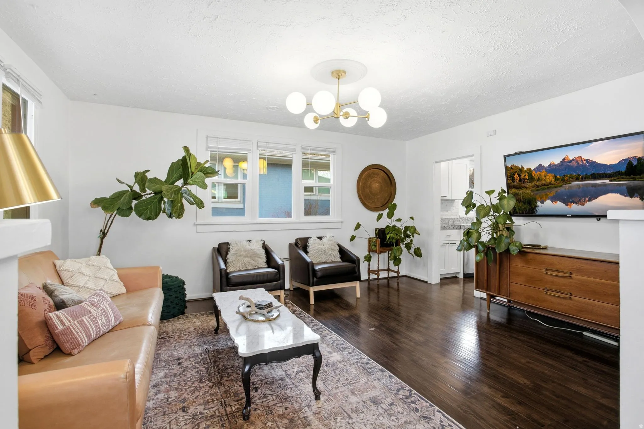 Living room with a textured ceiling, dark wood finished floors, and a chandelier