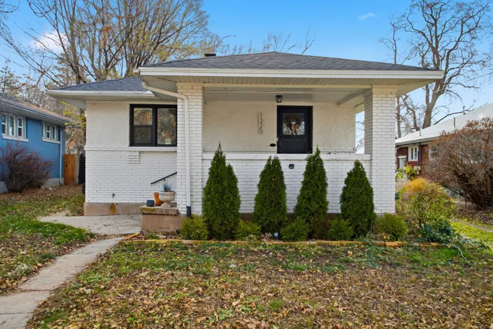 Bungalow with brick siding, covered porch, and a shingled roof