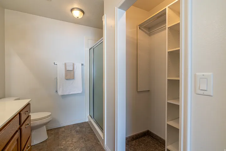 Full bath featuring a shower stall, a textured ceiling, stone finish flooring, a spacious closet, and vanity