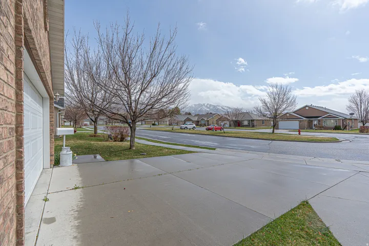View of green lawn with a residential view, driveway, and a garage