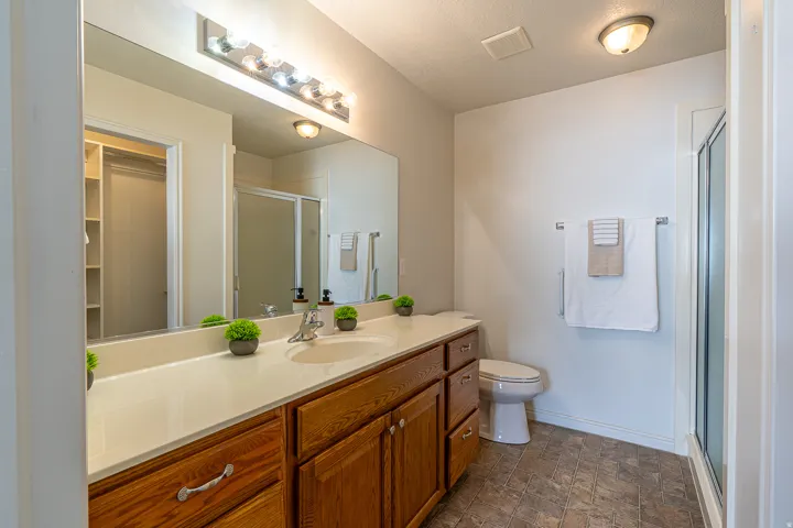 Full bath featuring vanity, a shower stall, stone finish flooring, a textured ceiling, and a walk in closet