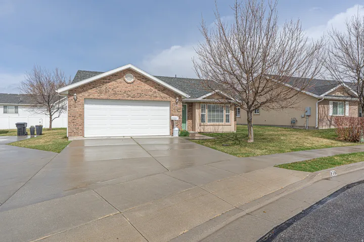 Single story home with a front lawn, driveway, brick siding, and a shingled roof
