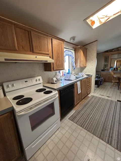 Kitchen with white electric range oven, light floors, brown cabinets & dishwasher