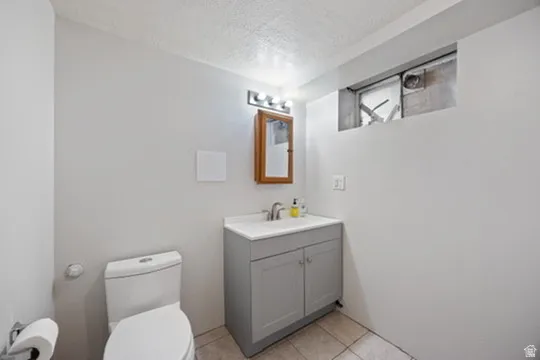 Half bathroom featuring a textured ceiling, vanity, and light tile patterned flooring