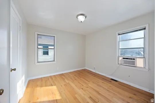 Unfurnished room featuring light wood-style floors, cooling unit, and plenty of natural light