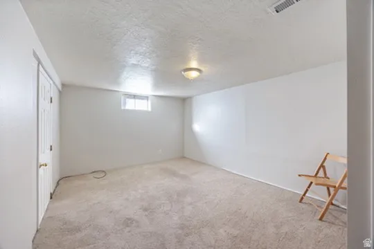 Basement featuring a textured ceiling and carpet flooring