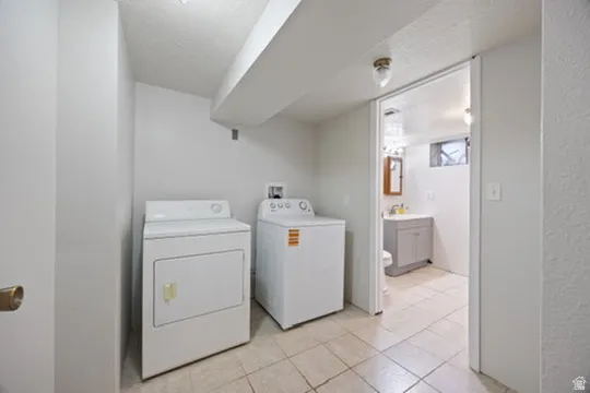 Washroom featuring washing machine and dryer, light tile patterned flooring, and a textured ceiling