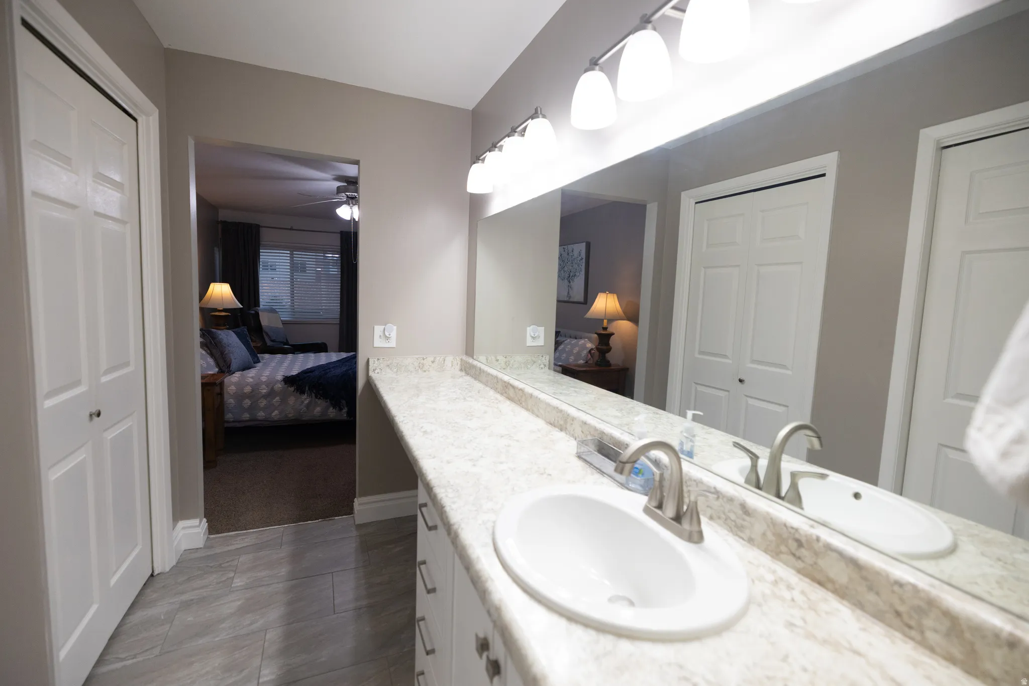 Ensuite bathroom featuring vanity, ceiling fan, and a closet