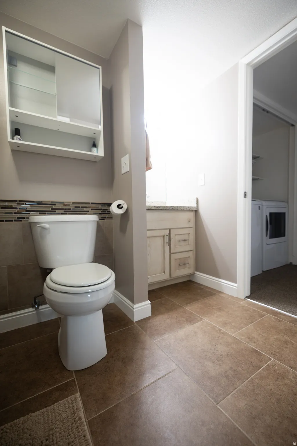 Bathroom with vanity, independent washer and dryer, and tile patterned flooring