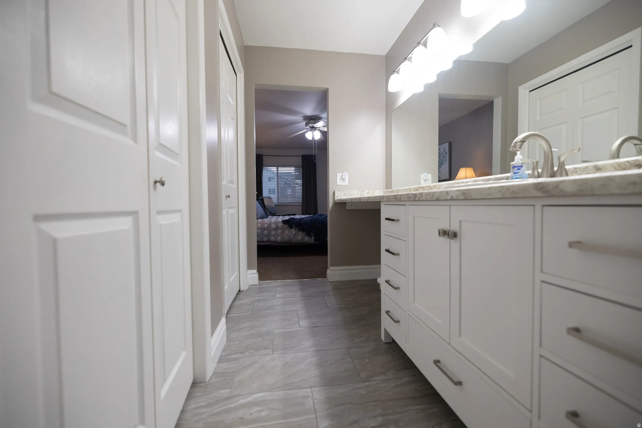 Ensuite bathroom featuring vanity, a closet, and a ceiling fan