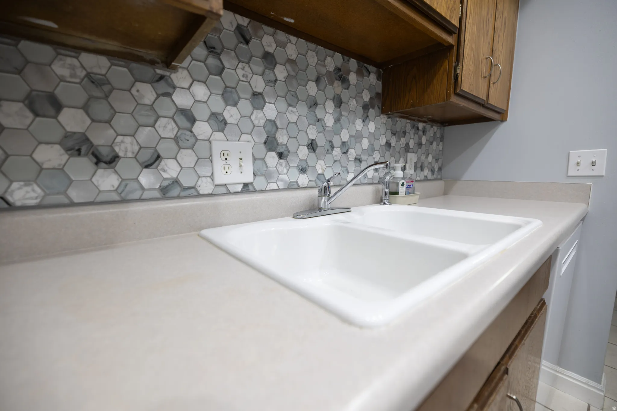 Kitchen view of light countertops and tasteful backsplash