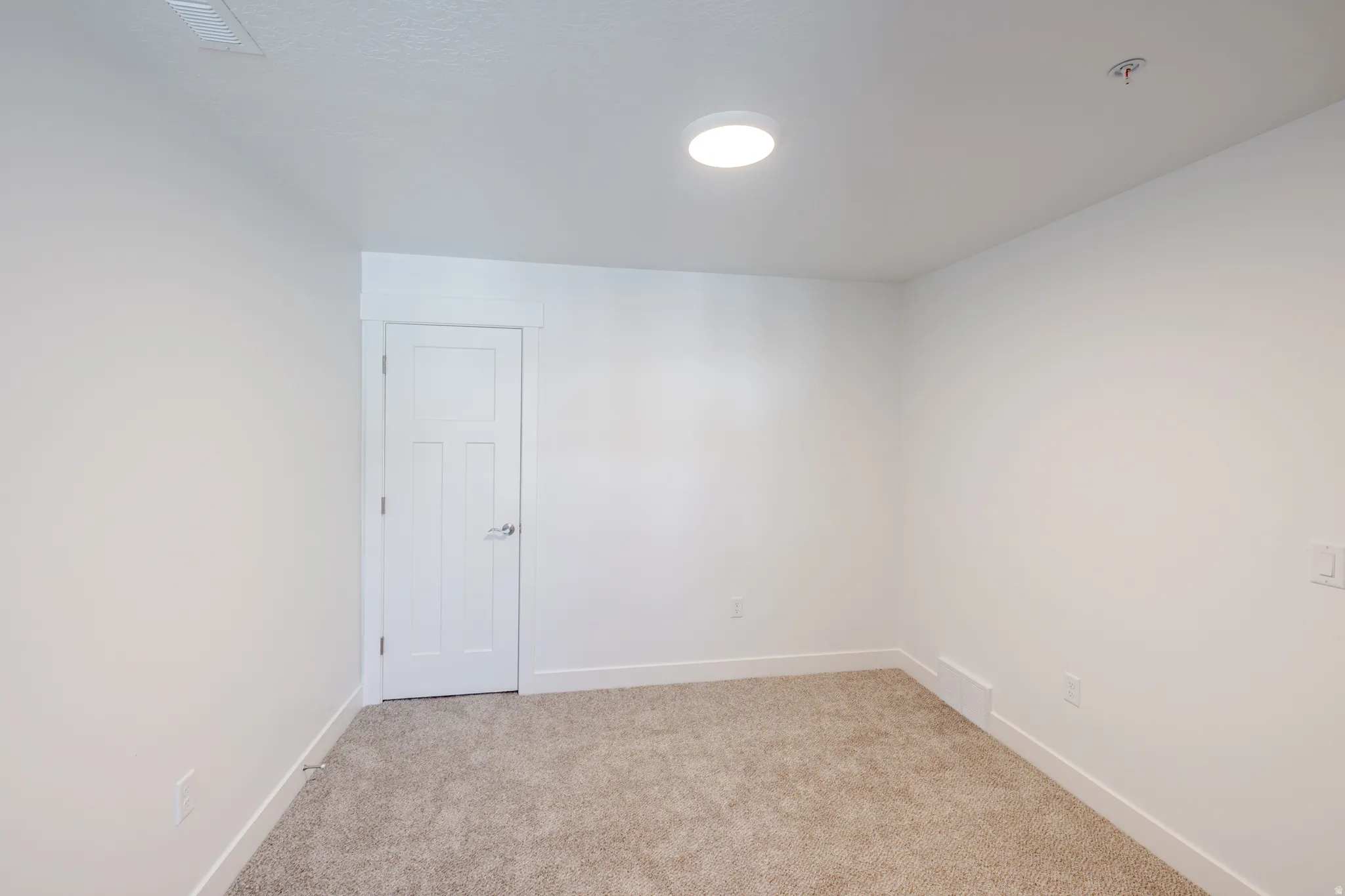 Spare room with light carpet and baseboards