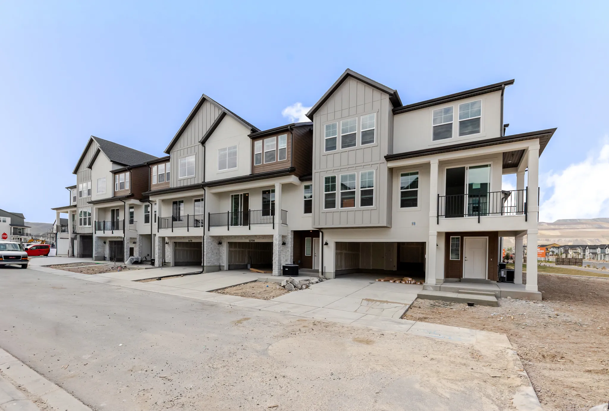View of front of home with board and batten siding, a residential view, concrete driveway, an attached garage, and a balcony