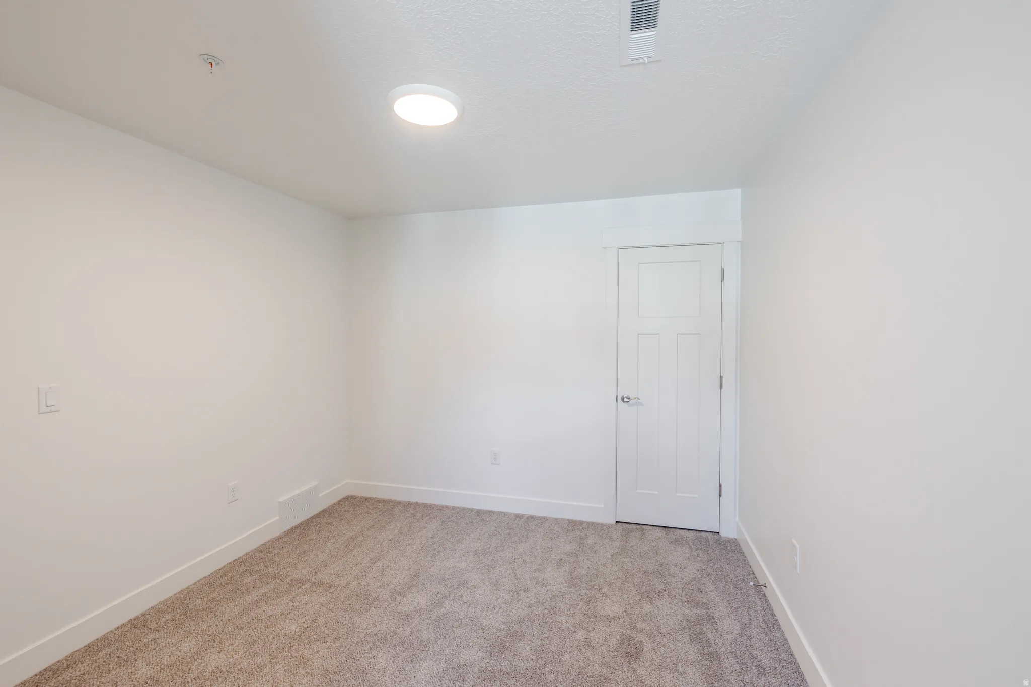 Unfurnished room featuring light carpet and baseboards