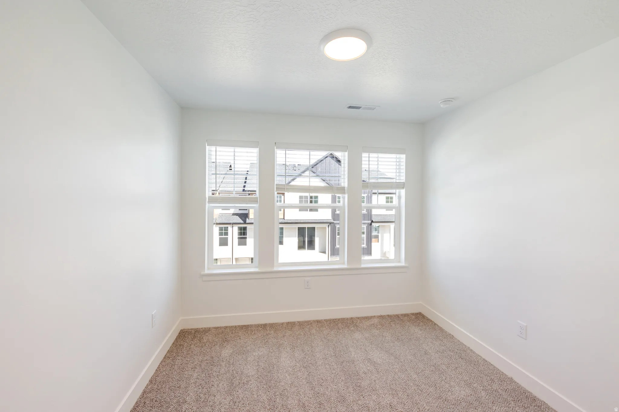 Spare room with light carpet and a textured ceiling
