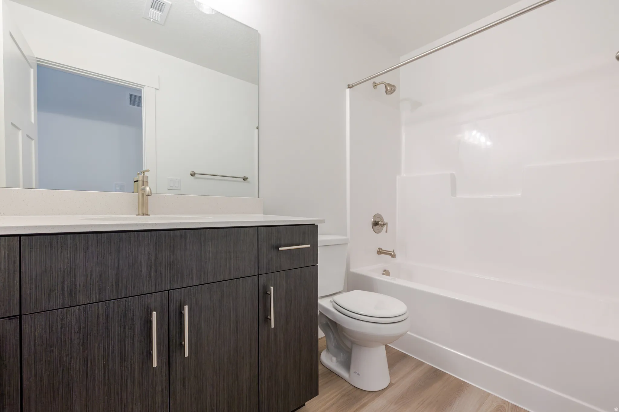 Bathroom featuring vanity, light wood-style flooring, and  shower combination